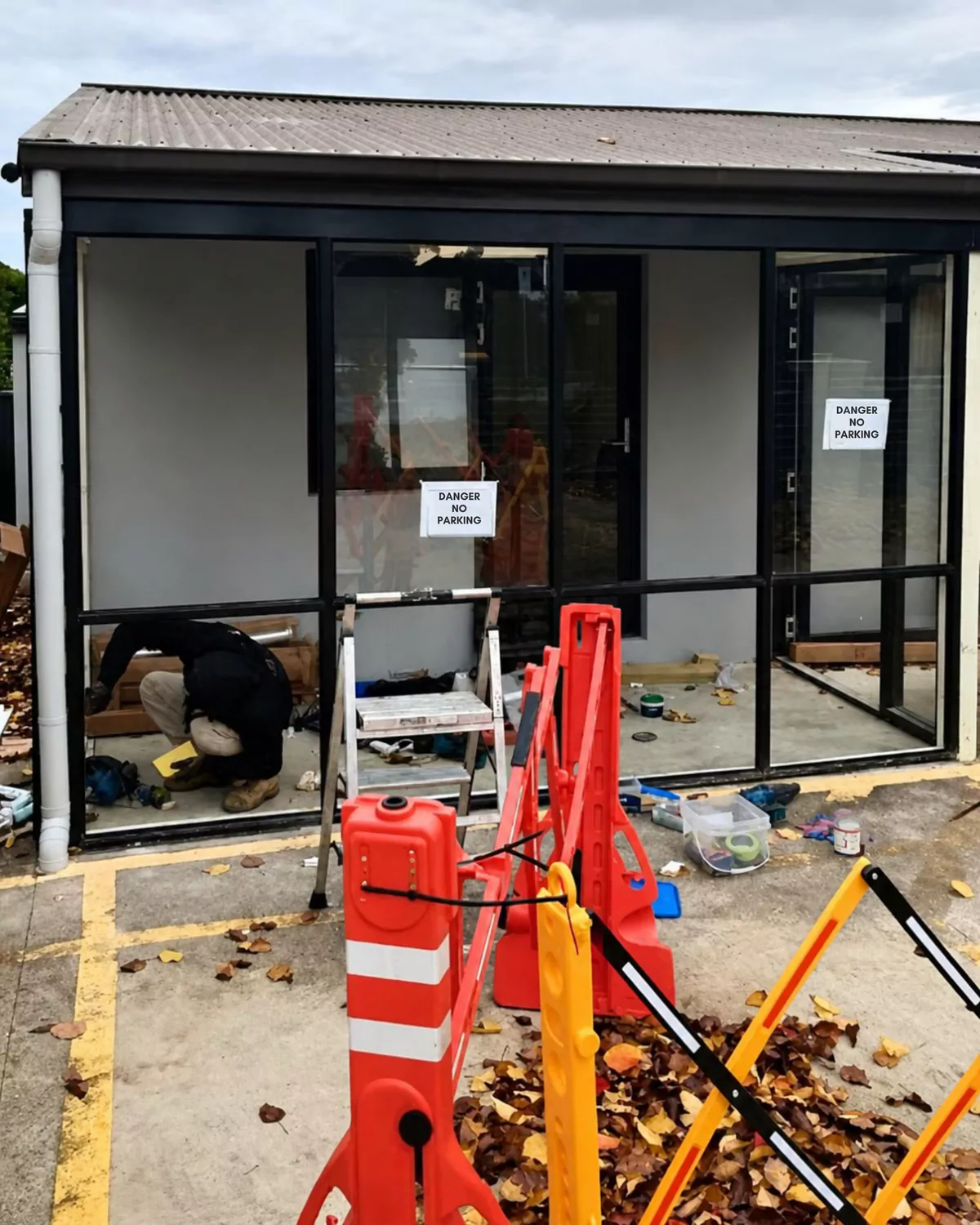 The site fenced off with barriers and danger signs while an installer works on the frame