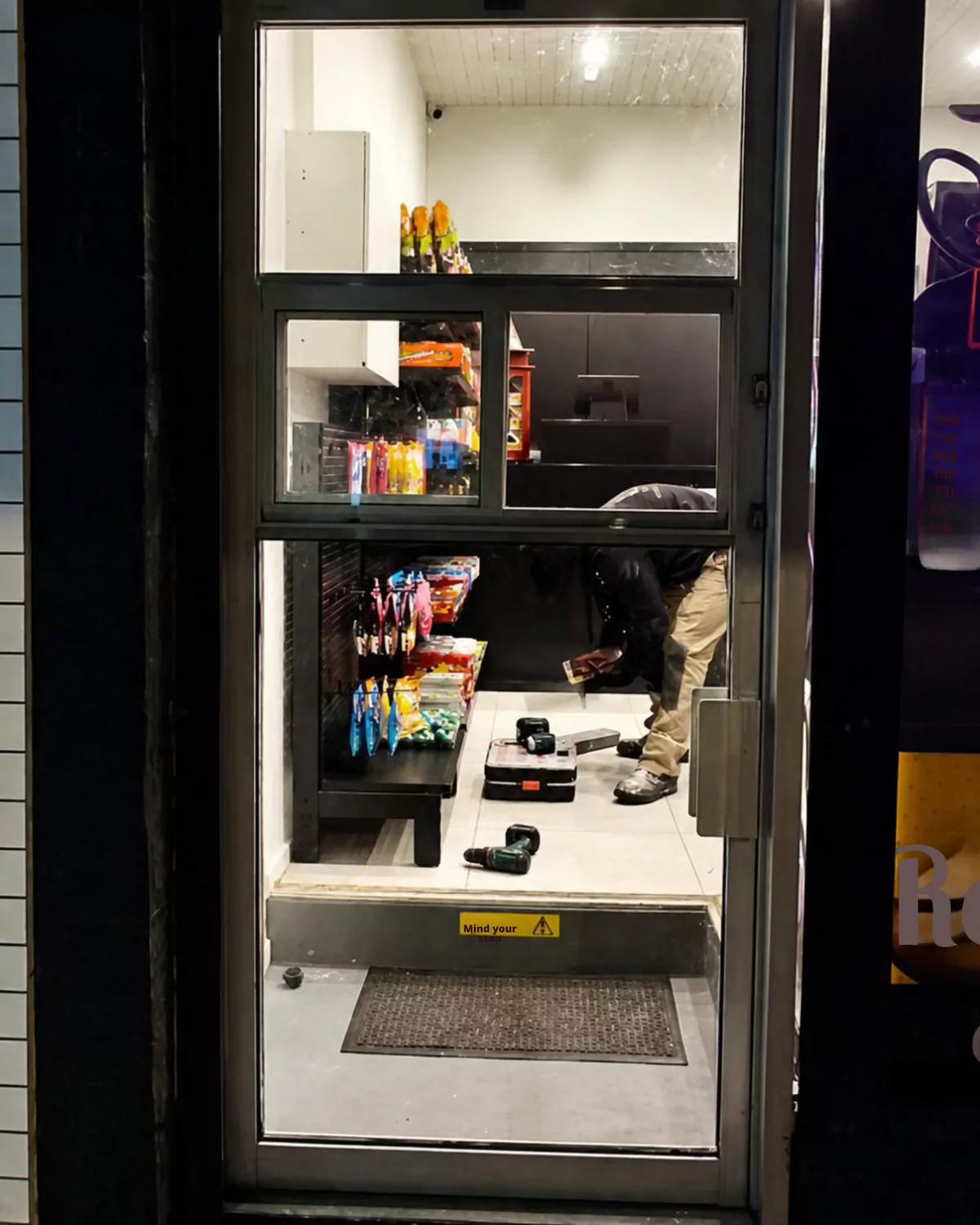 Before: the old dark-framed glass entry door of the mini mart, at night