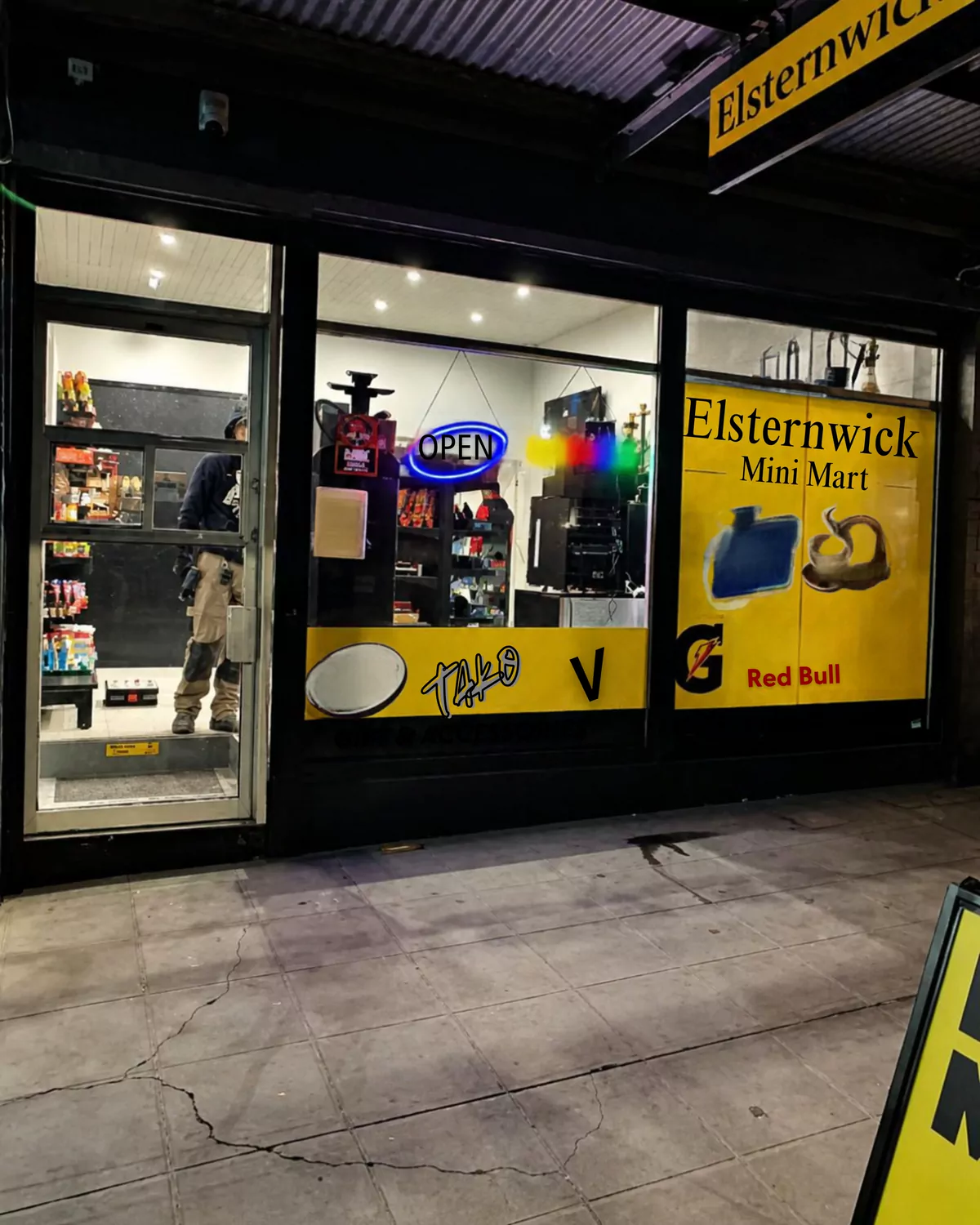 Before: the mini mart shopfront at night with the old dark-framed entry door